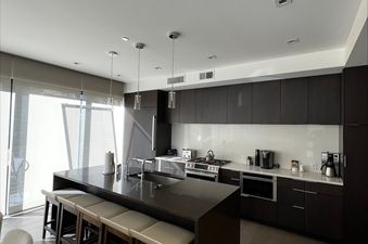 Modern kitchen with dark wood cabinets and a large central island with bar seating inside the Lift 4 Bedroom Suite.