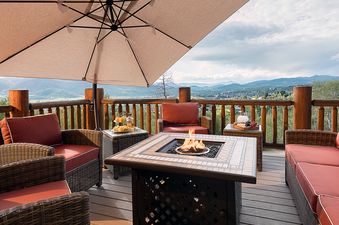 A cozy outdoor seating area on a balcony at Starfall Summit featuring a central fire pit table and stunning mountain views.