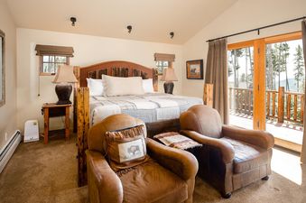 The bedroom at Moonlight Basin 4 Full Moon features a king bed with a rustic headboard and a view of the mountains from the large window. The room is decorated in a cozy and inviting style.