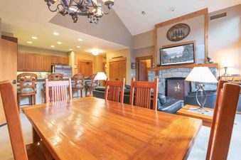 A living room with a fireplace, a large television, and a dining table with chairs.