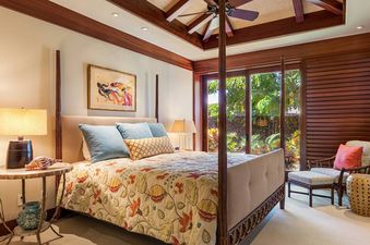 Beautifully decorated master bedroom at Hale Hoaloha with a four-poster bed and sliding doors leading to a lush tropical garden.
