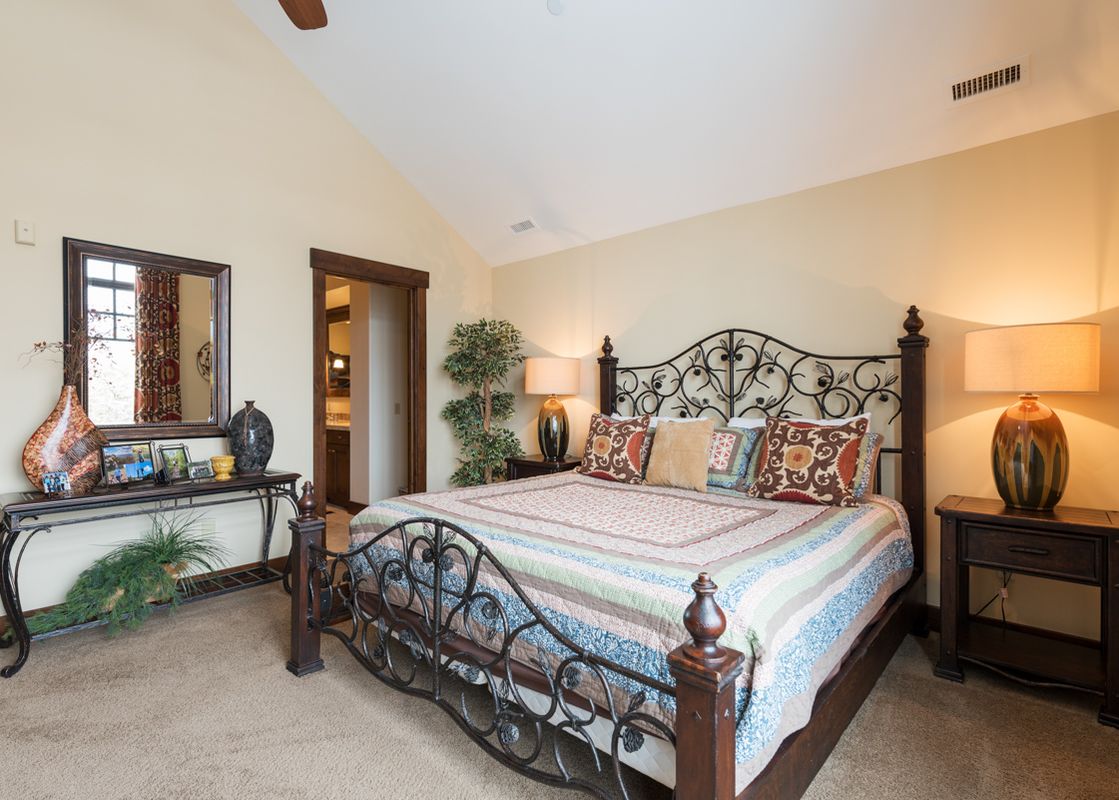 The master bedroom at Silver Star 902 features a wrought iron bed, two nightstands with lamps, a console table with a mirror, and an open doorway to the bathroom.