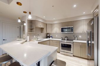 A modern kitchen with light cabinetry, quartz countertops, and stainless steel appliances in Torian Plum Creekside 714.