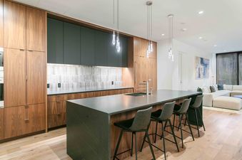 Modern kitchen in Founders Place 2503 featuring walnut cabinets and a large dark stone island with seating.