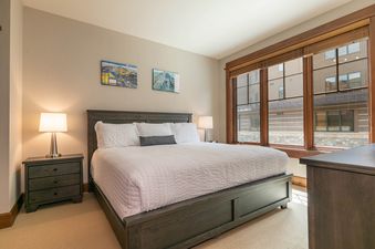 A bedroom with a king sized bed and a view of the snowy mountains outside.
