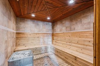A private sauna at Ptarmigan Hideout with wooden benches and ceiling, tiled walls, a sauna heater, and recessed lighting.