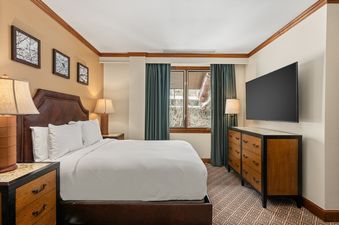 The luxurious bedroom in Ritz Carlton Club 3 Bedroom Penthouse 4302 features a leather headboard, plush bedding, and a flat-screen TV.