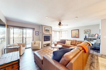 Living area with a leather sectional, fireplace, and balcony access at La Casa 04.