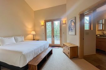 A cozy bedroom suite at Moose Creek 27 with a king bed and balcony doors.