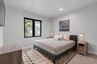 A serene bedroom at Dakota Haven with a large bed, nightstands with lamps, a window, and artwork.