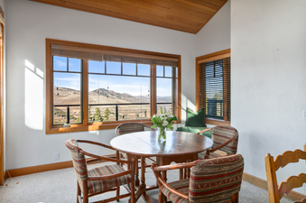 A dining room in a vacation rental with a view of mountains outside the window