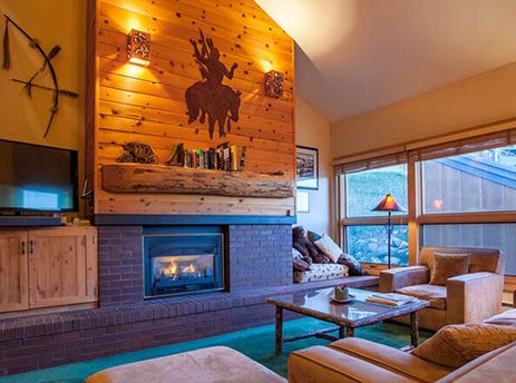 A cozy living room in Kutuk 201 with a roaring fireplace, comfortable seating, and rustic decor, offering an inviting space for relaxation.