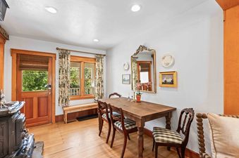 Dining room table with four chairs and a wood stove in the corner.