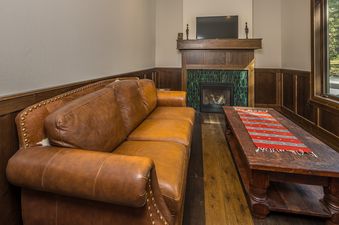 A cozy living room at Stony Creek Chalet features a large, comfortable leather sofa and a rustic wooden coffee table with a colorful runner.