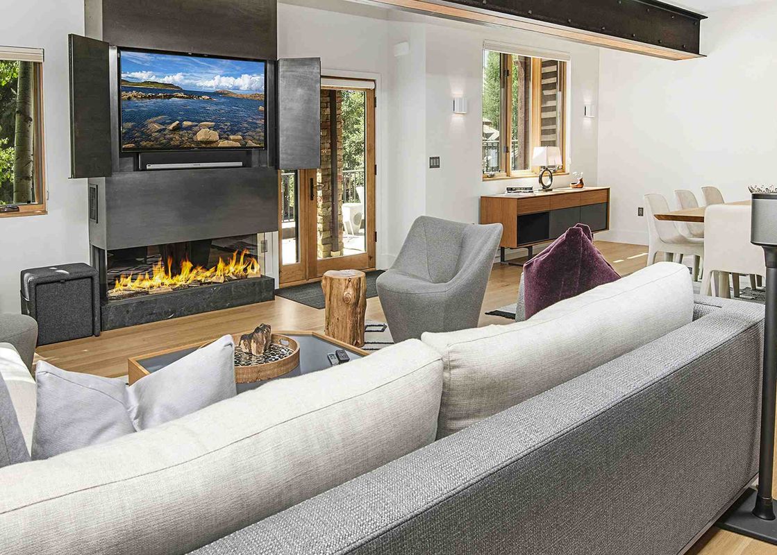 The living room of 1175 A Casolar Del Norte features a gas fireplace and a large sectional sofa with white cushions.