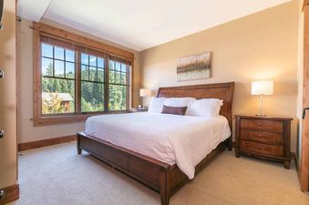 A bedroom with a king-size bed, wooden headboard, white bedding, and a bedside table with a lamp.