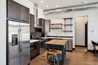 A modern kitchen with dark wood cabinets, stainless steel appliances, and a unique kitchen island.