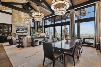 The spacious living area of Silver Buck features soaring ceilings, a stone fireplace, and expansive windows with stunning mountain views.