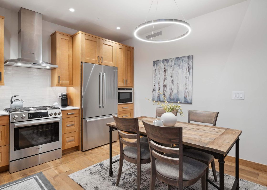 Riverfront Lodge 401 features a fully equipped kitchen with stainless steel appliances, a dining table for four, and hardwood floors.