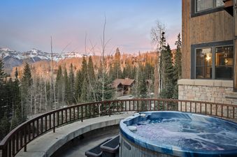A hot tub on a deck with mountains in the background at the Rocky Road Hideaway.
