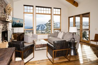 A spacious and luxurious lounge area in the Big View Luxury Suite with large windows showcasing snow-covered mountains and ski slopes.