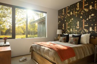 A sunlit bedroom with a queen bed and a scenic window view.