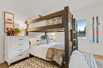 A bunk bed room at Quarry B8 with rustic decor, a white dresser, and a window offering an exterior view.