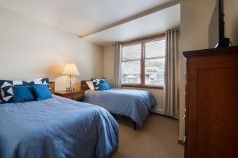 A cozy bedroom with two beds, each adorned with blue bedding and decorative pillows, inviting a restful night's sleep.