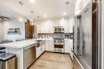 A modern kitchen in Blackstone Residence 1-B with white cabinets, stainless steel appliances, and a spacious island with a sink.