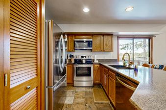 The kitchen at Silver Cliff Village 205 features modern stainless steel appliances, wood cabinetry, and a large window providing an exterior view.