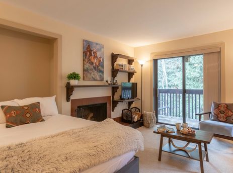 A cozy studio bedroom in Sleeping Indian W12 with a fireplace, private balcony, and seating area.