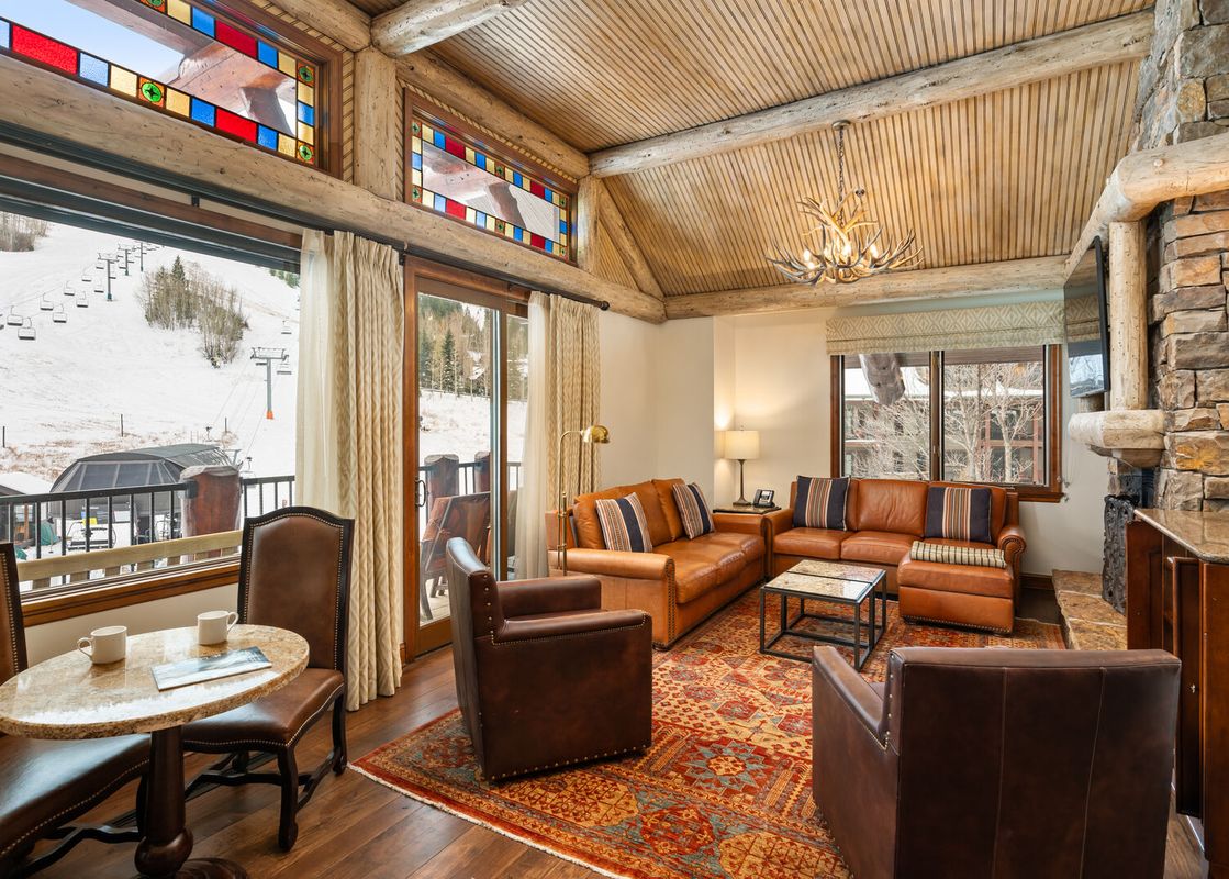The Ritz Carlton Club 3 Bedroom Penthouse 4302 living area features comfortable leather sofas, stone fireplace, and mountain views.