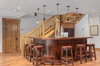 A rustic home bar with wooden stools and log stairs at Forest Edge.