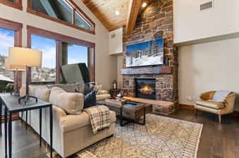 Black Diamond Lodge Four Bedroom Deluxe 241 living room with a stone fireplace and large windows with a view.