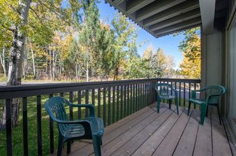 Private balcony at Whiteridge B1 with green plastic chairs and views of autumn trees.