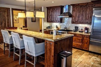 A modern, upscale kitchen with dark wood cabinets, granite countertops, and stainless steel appliances at Arrabelle 1 Bedroom.