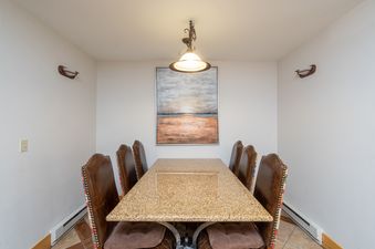 Dining area in Bear Creek Lodge 204 with a table and chairs. The table is made of granite and has a brown finish. The chairs are upholstered in a brown leather and have a studded design.