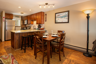 A well-lit kitchen and dining area with modern appliances and a wooden dining set.