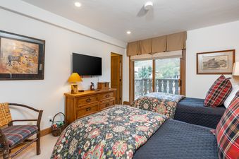 The interior view of the Bridge Street Lodge 3 Bedroom Diamond Unit 309, with twin beds, a dresser, and a large window overlooking the exterior.