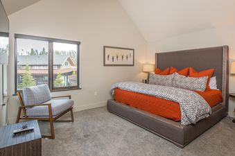 A cozy bedroom with a plush king bed and a view of the forest from the window.