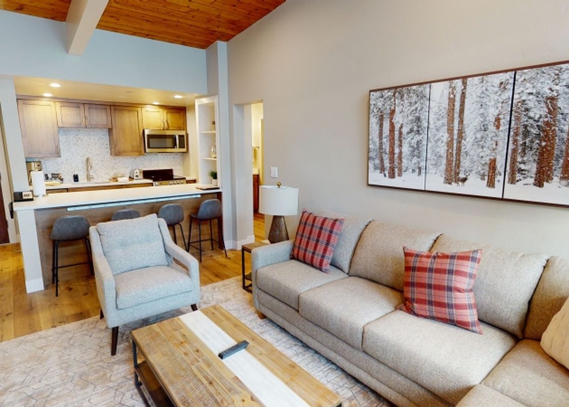 A living room with a couch and a coffee table in front of a large window with a view of a snowy forest