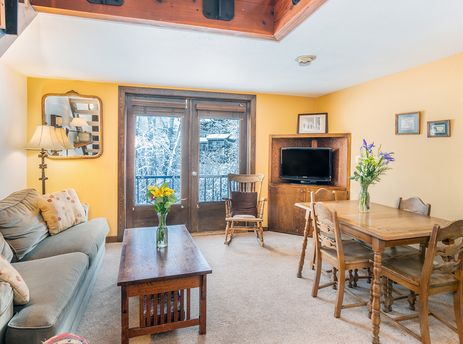 Living area of Manitou Lodge 7 with a comfortable couch, dining table, and a view of a snowy landscape.