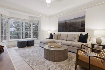 Living room area in The Charter C250 with a large bay window, sectional sofa, and round coffee table.