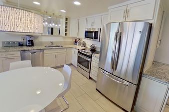 The kitchen at Crestwood 2307 features stainless steel appliances, white cabinetry, and granite countertops.