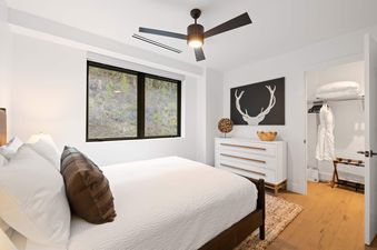A modern bedroom in Frontgate 429 features a large window with a view of the outdoors, a comfortable bed, and a stylish dresser.