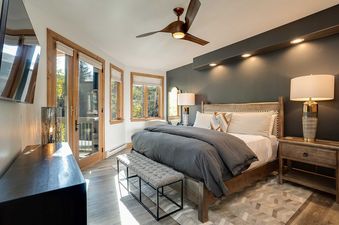 A modern bedroom at Chateau Chamonix CX332 featuring a large bed, balcony access, and contemporary furnishings, bathed in natural light.
