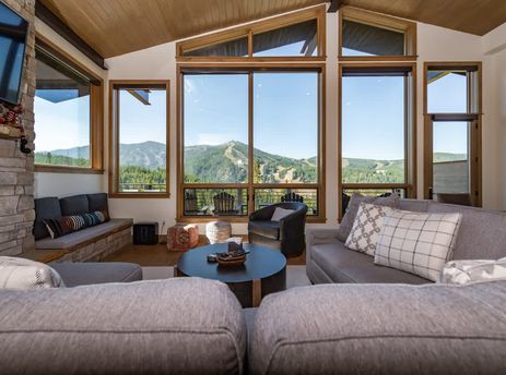 The living area of Apex Manor is spacious and well-lit, featuring comfortable seating arrangements and large windows that offer panoramic views of the surrounding mountains and ski slopes.