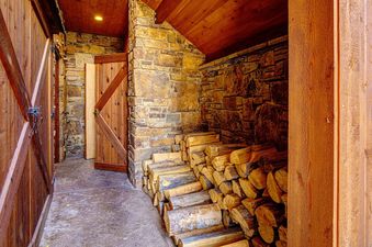 A rustic log cabin with a wood-burning fireplace and stacked firewood.