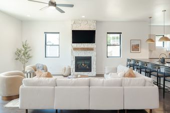 The contemporary living room at Alpine Proper showcasing a white stone fireplace and a large cream sectional sofa.