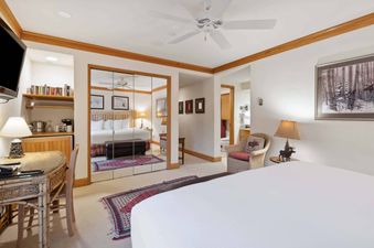 A spacious and inviting bedroom at The Charter E435, featuring a king-sized bed, a desk with a mini-fridge and coffee maker, and rustic decor.
